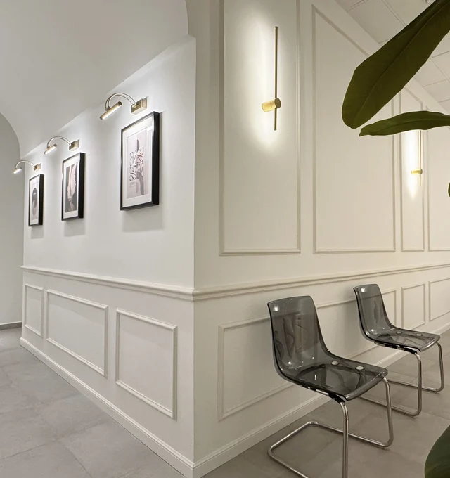 Area d’attesa di Eterna Polimedico con sedute, quadri e illuminazione a parete.